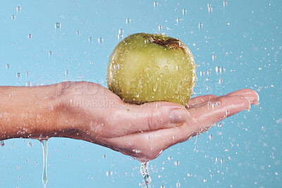 Buy stock photo Vegan, water and a hand with an apple on a blue background for nutrition, cleaning or wellness. Diet, food and closeup of a person with a fruit in palm for a detox isolated on a studio backdrop