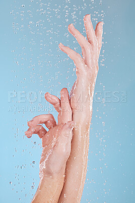 Buy stock photo Water drops, skin and person washing hands in studio on blue background for hygiene or hydration. Cleaning, wellness and skincare with a woman in the bathroom for sustainability or to remove bacteria