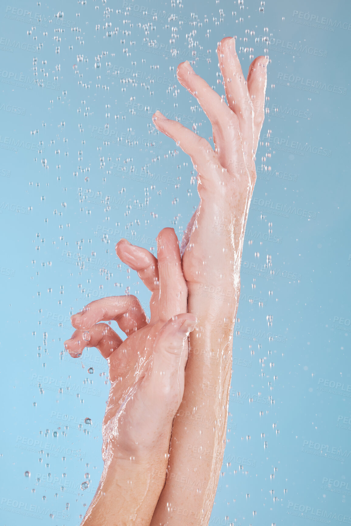 Buy stock photo Water drops, skin and person washing hands in studio on blue background for hygiene or hydration. Cleaning, wellness and skincare with a woman in the bathroom for sustainability or to remove bacteria