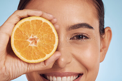 Buy stock photo Closeup woman, portrait and orange for vitamin C, diet or skincare against a blue studio background. Face of happy person smile with organic citrus fruit in natural nutrition, spa or facial treatment