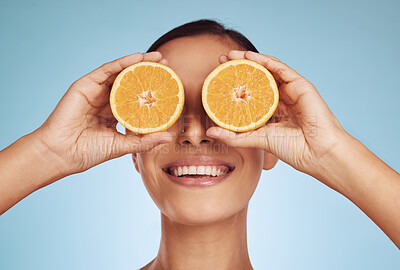 Buy stock photo Happy woman, eyes and orange for natural vitamin C, skincare or diet against a blue studio background. Face of person smile with organic citrus fruit for nutrition, dermatology or healthy wellness