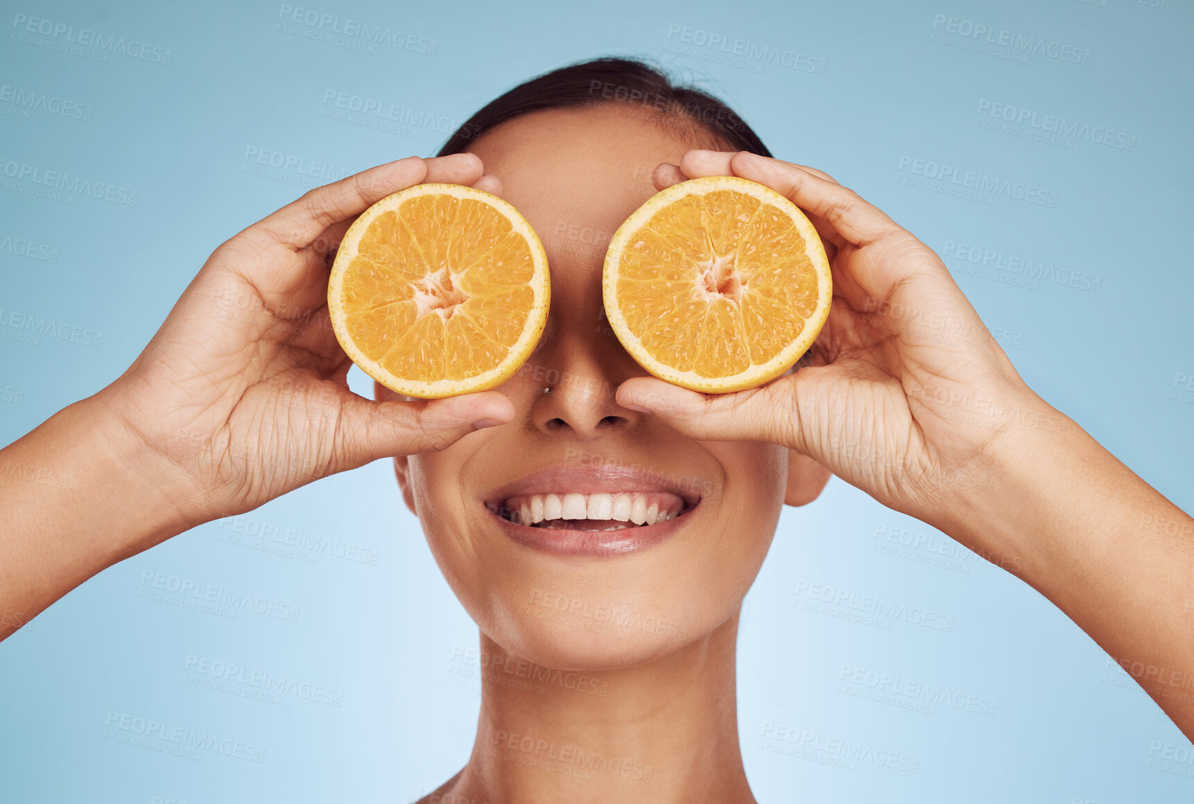 Buy stock photo Happy woman, eyes and orange for natural vitamin C, skincare or diet against a blue studio background. Face of person smile with organic citrus fruit for nutrition, dermatology or healthy wellness