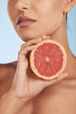 Buy stock photo Woman, hands and grapefruit for vitamin C, skincare or diet against a blue studio background. Closeup of female person with organic citrus fruit for natural nutrition, dermatology or healthy wellness