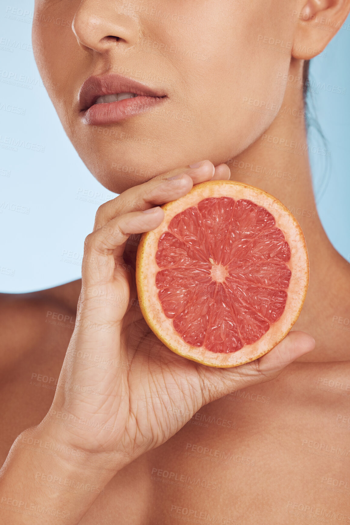 Buy stock photo Woman, hands and grapefruit for vitamin C, skincare or diet against a blue studio background. Closeup of female person with organic citrus fruit for natural nutrition, dermatology or healthy wellness