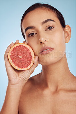 Buy stock photo Woman face, grapefruit for vitamin C and natural skincare or diet against a blue studio background. Portrait of female person with organic citrus fruit for nutrition, dermatology or healthy wellness