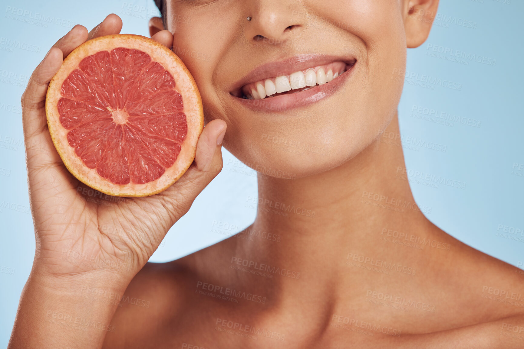 Buy stock photo Happy woman, hands and grapefruit for vitamin C, diet or skincare against a blue studio background. Closeup of female person smile with organic fruit for natural nutrition, health and dental wellness