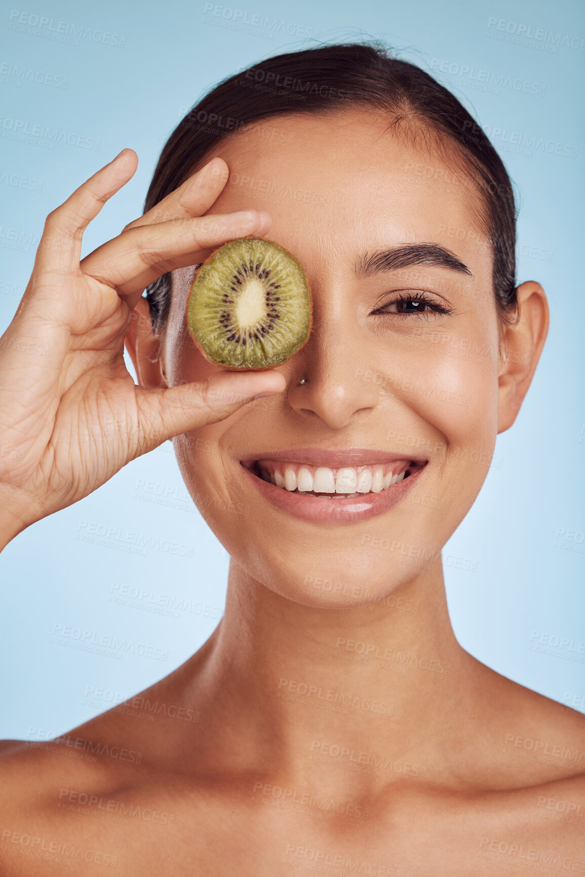 Buy stock photo Skincare portrait, kiwi and woman with eye beauty, cosmetics and natural product, health and vitamin c. Face of young happy person or model, green fruits and dermatology on a studio, blue background