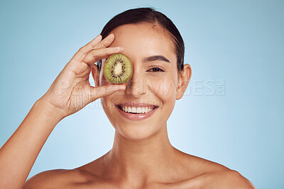 Buy stock photo Beauty portrait, kiwi and woman with eye skincare, cosmetics and natural product, health and vitamin c. Face of young happy person or model, green fruits and dermatology on a studio, blue background