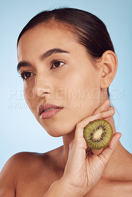 Buy stock photo Woman, hands and kiwi in skincare for diet or natural nutrition against a blue studio background. Female person or model with organic fruit for healthy wellness, beauty or facial spa treatment