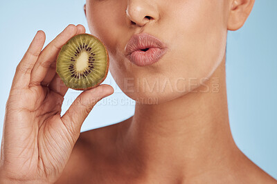 Buy stock photo Woman, kiwi and skincare with natural beauty, closeup and girl on a blue studio background. Zoom, model or mouth with a fruit, detox or organic grooming with luxury lips or pouting with dermatology