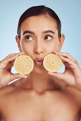 Buy stock photo Woman, hands and lemon for skincare detox, diet or collagen against a blue studio background. Female person or model holding organic citrus fruit for natural nutrition, anti aging or facial treatment