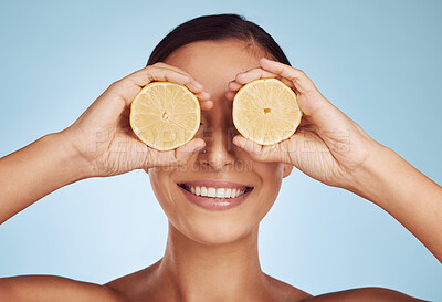 Buy stock photo Happy woman, hands and lemon eyes for skincare detox, diet or collagen against a blue studio background. Female person with organic citrus fruit for natural nutrition, anti aging or facial treatment