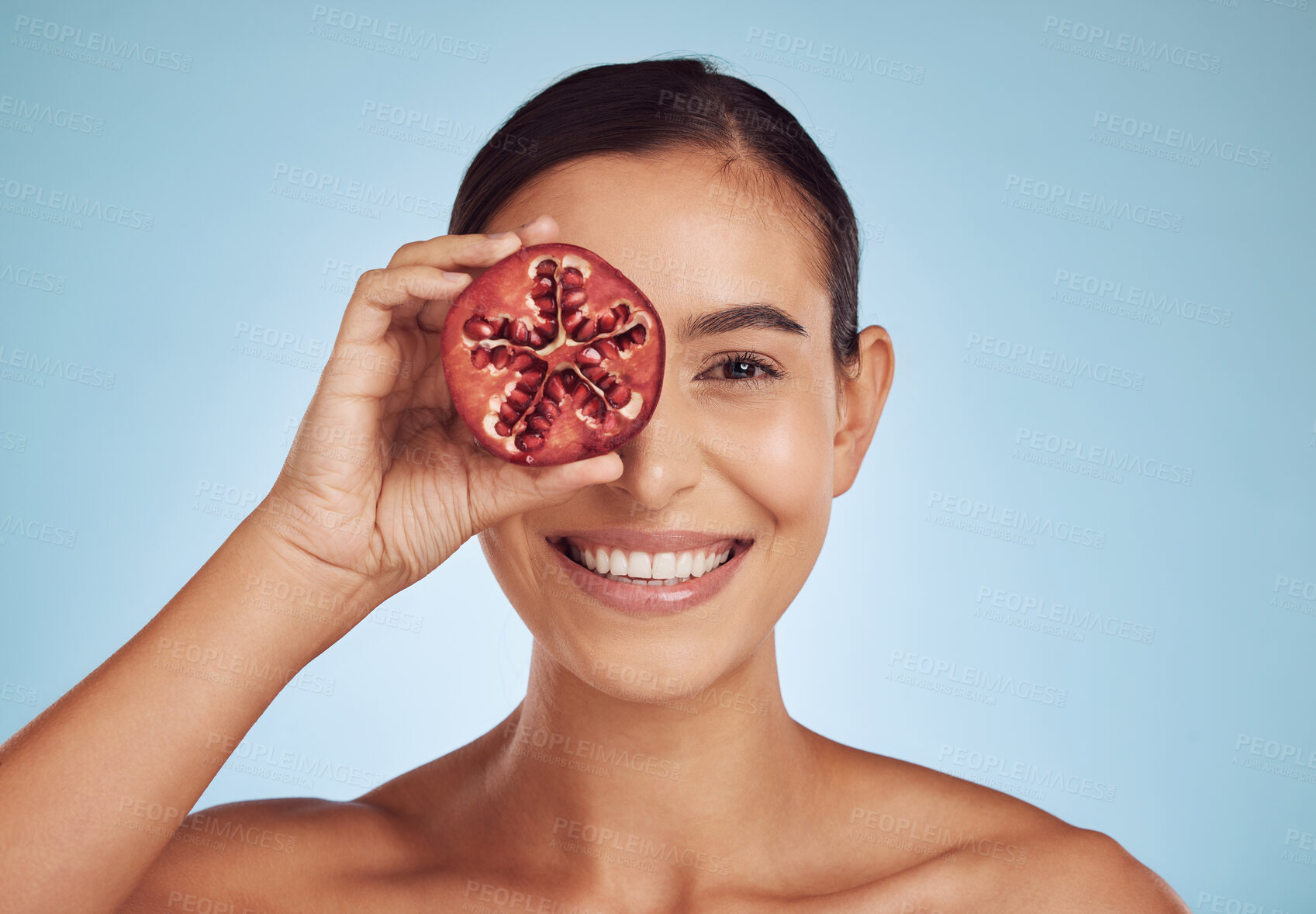 Buy stock photo Woman, beauty portrait and pomegranate for skincare, cosmetics and natural facial product or vitamin c benefits. Face of person or model with red fruits for eye dermatology on studio blue background