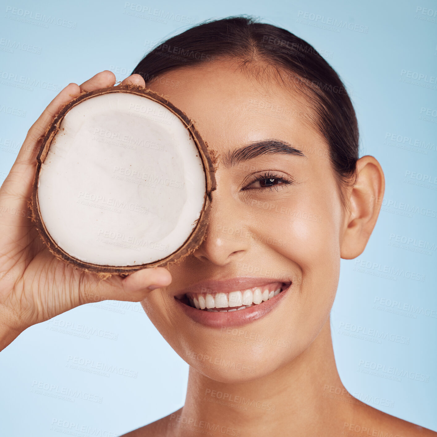 Buy stock photo Young woman, coconut fruit and eye beauty, skincare or vegan cream on studio, blue background. Happy person or model with natural product for dermatology, eco friendly cosmetics and oil benefits