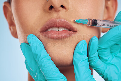 Closeup, woman and plastic surgery with a needle, lip filler and cosmetics against a blue studio background. Zoom, female person or model with injection, dermatology and beauty with medical procedure