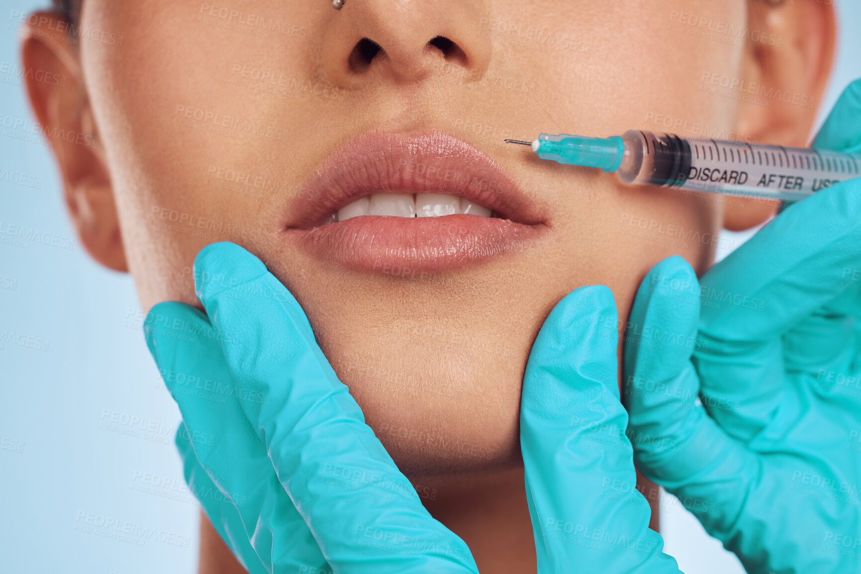 Buy stock photo Closeup, woman and plastic surgery with a needle, lip filler and cosmetics against a blue studio background. Zoom, female person or model with injection, dermatology and beauty with medical procedure