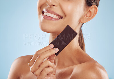 Buy stock photo Smile, skincare and woman with chocolate for beauty isolated on a blue background. Happy, candy and model with food, cacao and dessert, sweets and sugar for eating, cholesterol and natural cosmetics