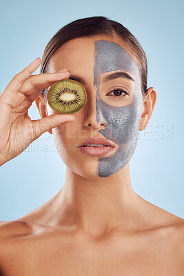 Buy stock photo Portrait, kiwi and mask for skincare with a woman in studio on a blue background for antiaging beauty. Face, facial and fruit with an attractive young female holding a berry for organic treatment