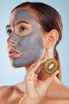 Buy stock photo Thinking, kiwi and mask for beauty with a woman in studio on a blue background for antiaging skincare. Face, facial and fruit with a young female model holding a berry for natural organic treatment