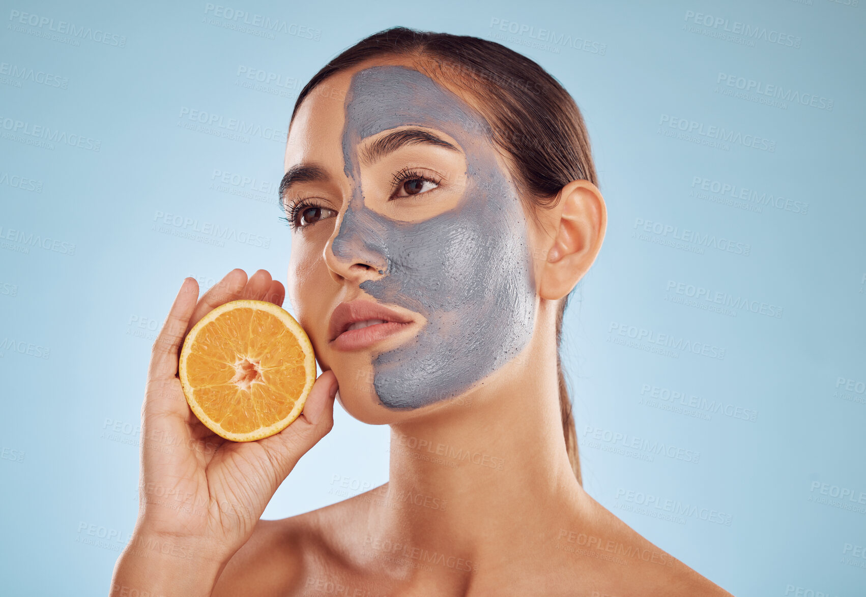 Buy stock photo Woman, orange and face mask for skincare, vitamin C or natural nutrition against a blue studio background. Female person or model with healthy organic citrus fruit for beauty spa or facial treatment