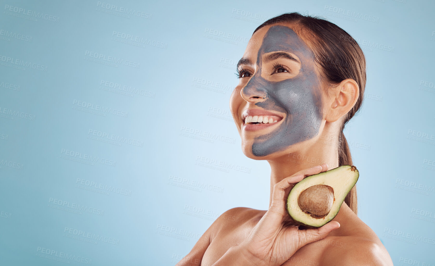 Buy stock photo Mockup, avocado and mask for beauty with a woman in studio on a blue background for antiaging skincare. Facial, smile and idea with an attractive young person holding a fruit for detox or treatment