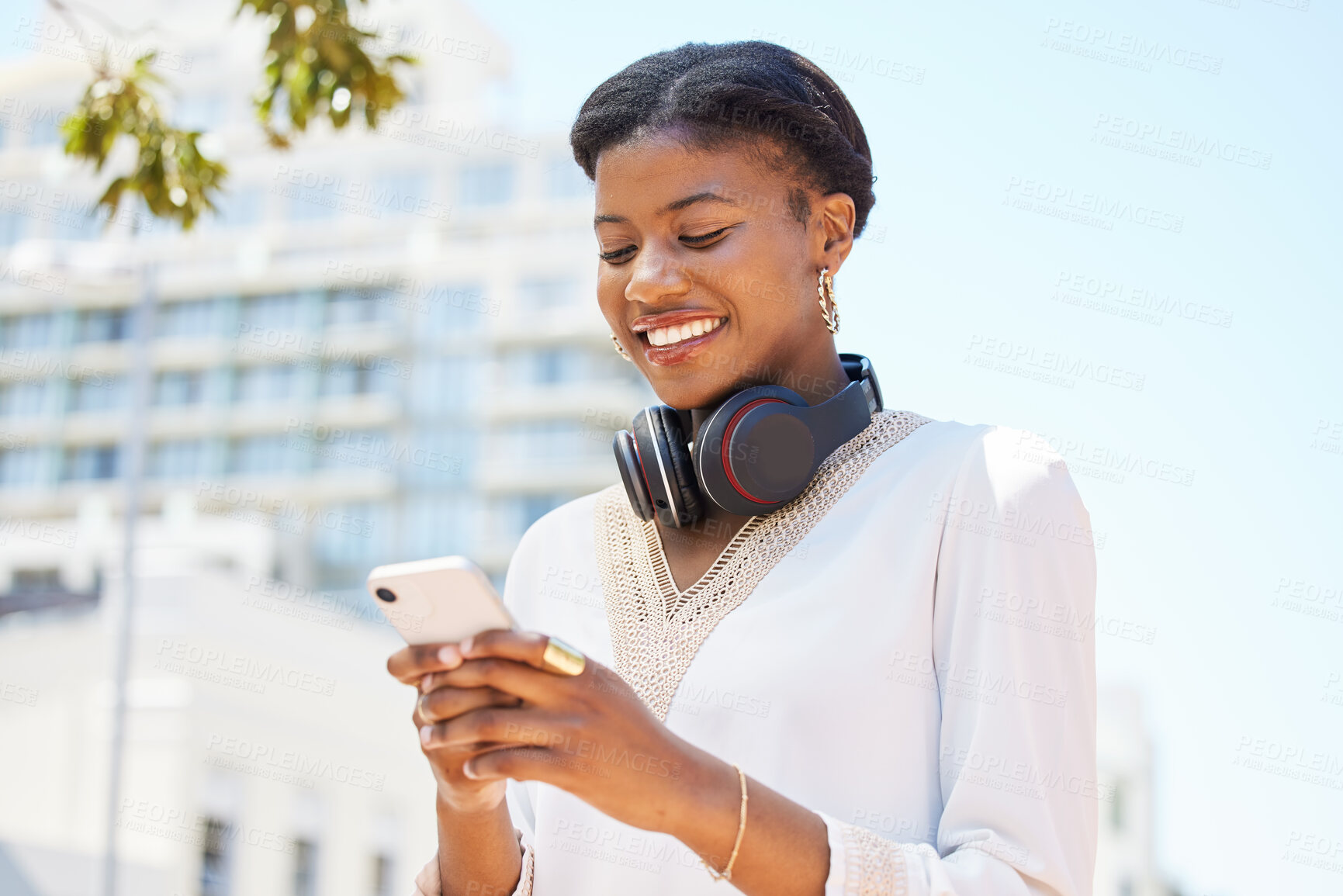 Buy stock photo Phone, city and music with a business black woman typing a text message while walking to work outdoor. Mobile, headphones and social media with a happy employee commuting in an urban town with flare