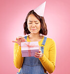 Birthday present, studio box and Asian woman stress over package, ribbon opening fail or party event. Problem crisis, bad gift mistake and Japanese person with doubt, unsure or sad on pink background