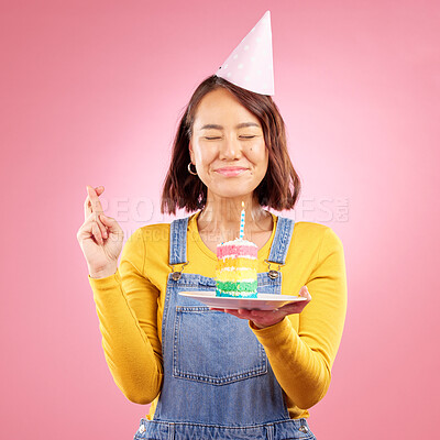 Buy stock photo Birthday cake candle, wish and Asian woman with fingers crossed, hope and celebrate party, present or studio gift. Praying, emoji icon sign and person with dessert, candy or sweets on pink background