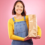 Woman, paper bag and studio portrait with shopping, discount or groceries with smile by pink background. Japanese gen z girl, retail customer and package for product, sale and excited for cheap deal