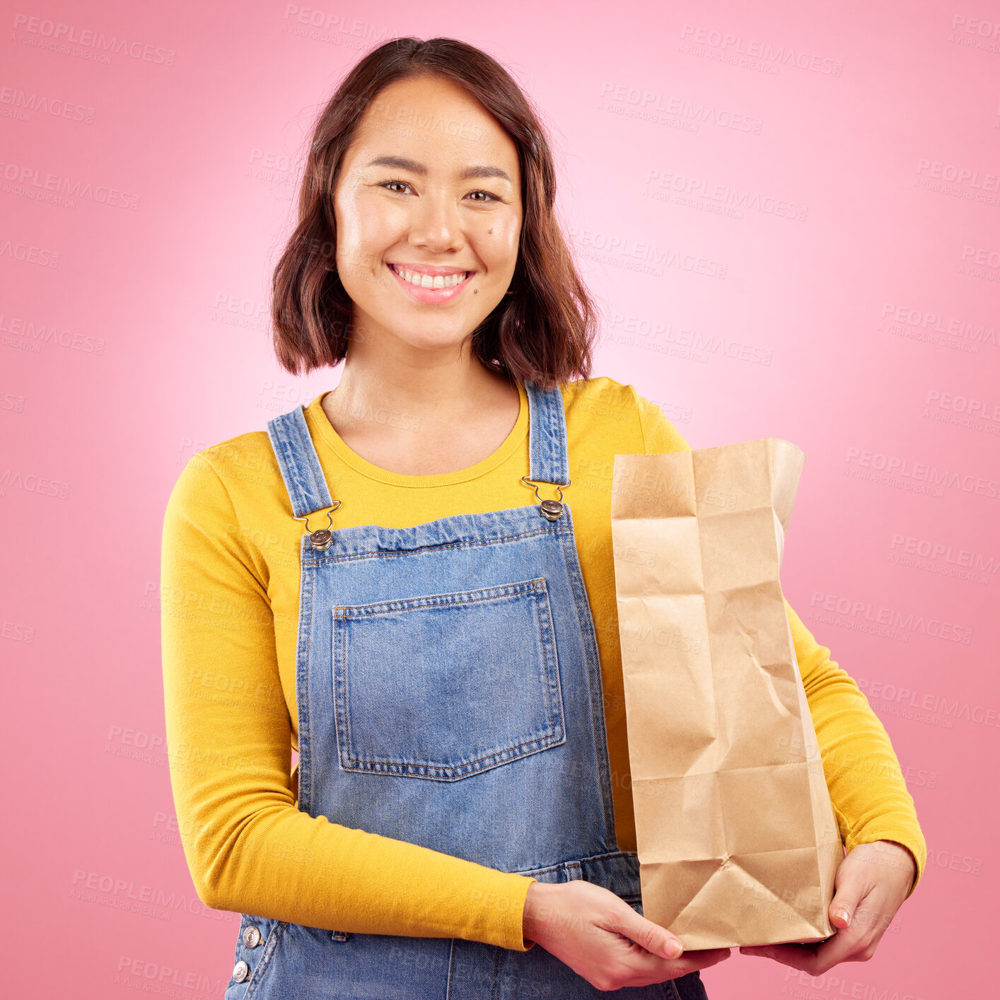 Buy stock photo Woman, paper bag and studio portrait for grocery shopping, discount or choice with smile by pink background. Japanese gen z girl, retail customer and package for product, sale or happy for cheap deal