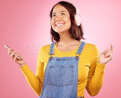 Buy stock photo Woman, headphones and phone with smile, studio and thinking with music, ideas and relax by pink background. Happy gen z girl, Japanese student and audio tech for listening with streaming subscription