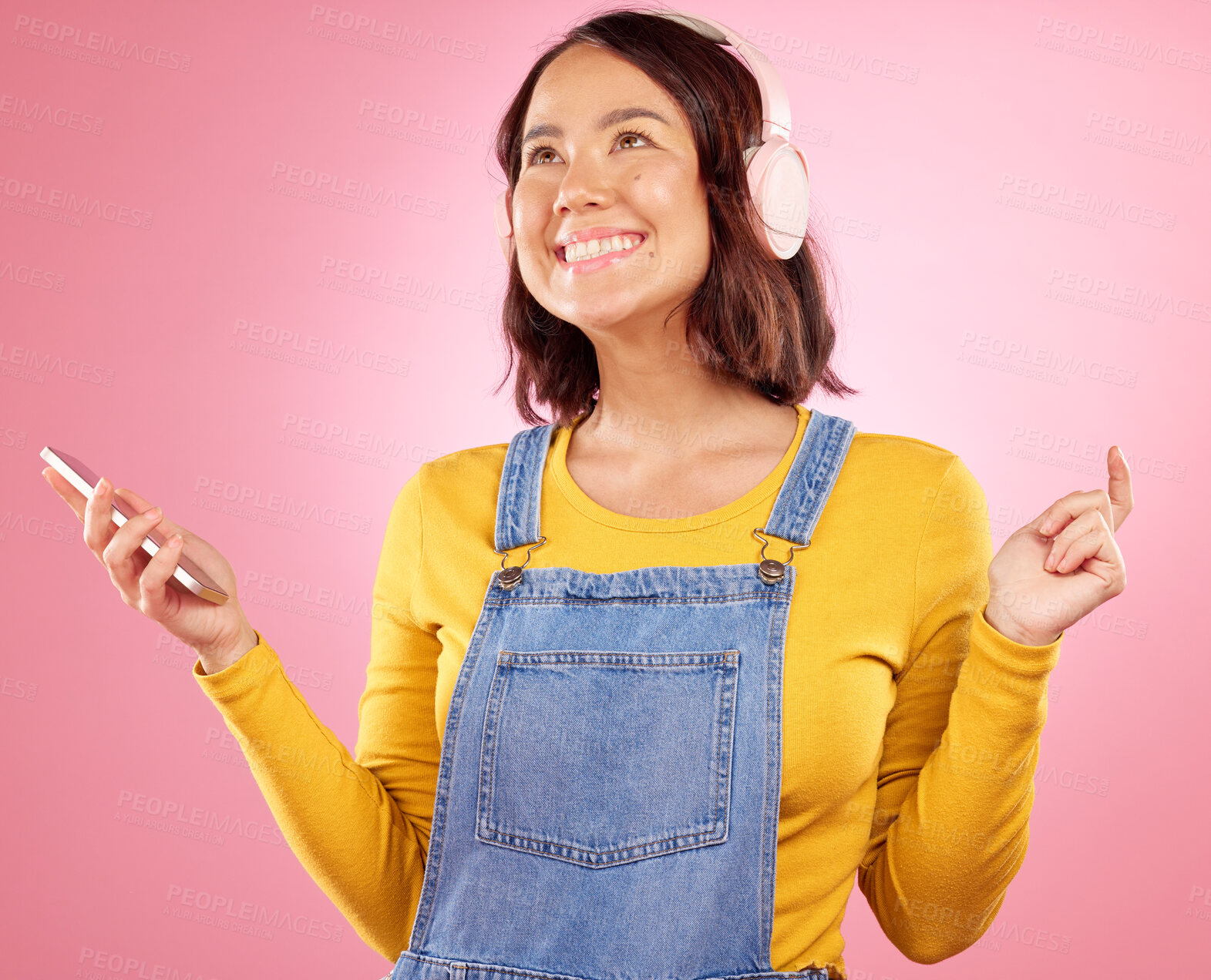 Buy stock photo Woman, headphones and phone with smile, studio and thinking with music, ideas and relax by pink background. Happy gen z girl, Japanese student and audio tech for listening with streaming subscription