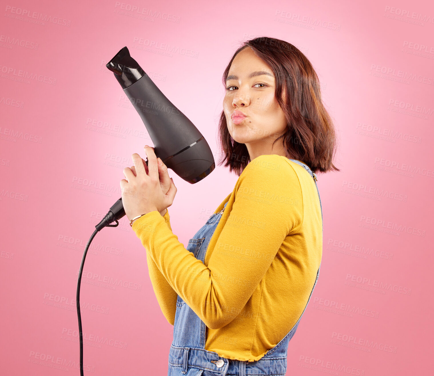 Buy stock photo Hairdryer, kiss and hair care with portrait of woman in studio for hairdresser, beauty and cosmetics. Shampoo, salon and hairstyle with funny face of person on pink background for product and glow