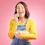 Portrait, asian woman and eating popcorn in studio while watching movie, film or cinema show on pink background. Happy female model, bowl or snack to enjoy streaming, subscription or tv entertainment