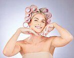 Hair care, rollers and portrait of woman in a studio doing a natural, beautiful and curly hairstyle. Self care, happy and attractive female model with curlers for beauty isolated by a gray background