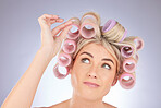 Hairstyle, curlers and woman thinking in a studio doing a natural, beautiful and curly hair care. Self care, confused and attractive female model with rollers for beauty isolated by a gray background