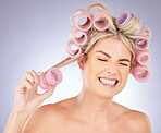 Woman, hair care and pain with roller for beauty in studio isolated on a white background. Happy, curlers and model with hairstyle for aesthetic, cosmetics and salon treatment for natural growth.