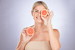 Skincare, portrait and happy woman with grapefruit for natural facial cleaning, beauty self care or vitamin C glow. Nutritionist face, studio and person with fruit detox benefits on purple background