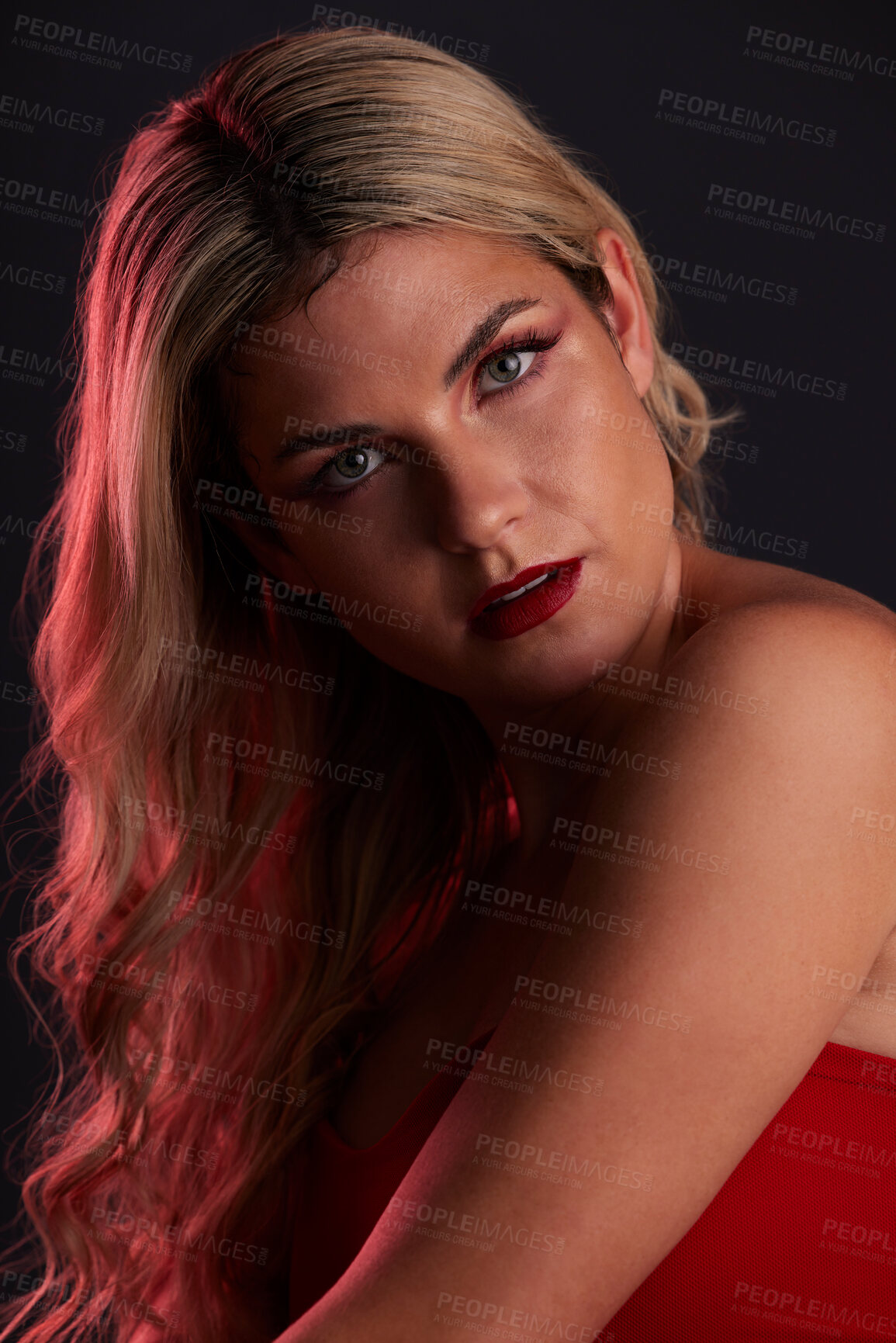 Buy stock photo Portrait, luxury and makeup with a model woman in studio on a dark background in red lighting for desire. Face, beauty or skincare with a young female person posing for natural feminine confidence