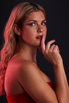 Portrait, beauty and sensual with a model woman in studio on a dark background in red lighting for desire. Face, makeup or lipstick with a young female person posing for natural feminine confidence