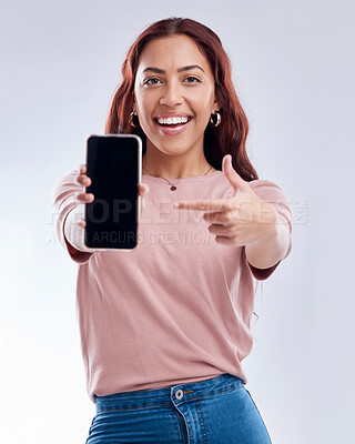 Buy stock photo Woman is pointing at phone screen, mockup and advertising, mobile app ads on white background. Website promo, marketing and female brand ambassador in portrait with social media branding in studio