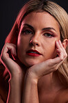 Portrait, skincare and luxury with a model woman in studio on a dark background in red lighting for desire. Face, beauty and makeup with a young female person posing for natural feminine confidence