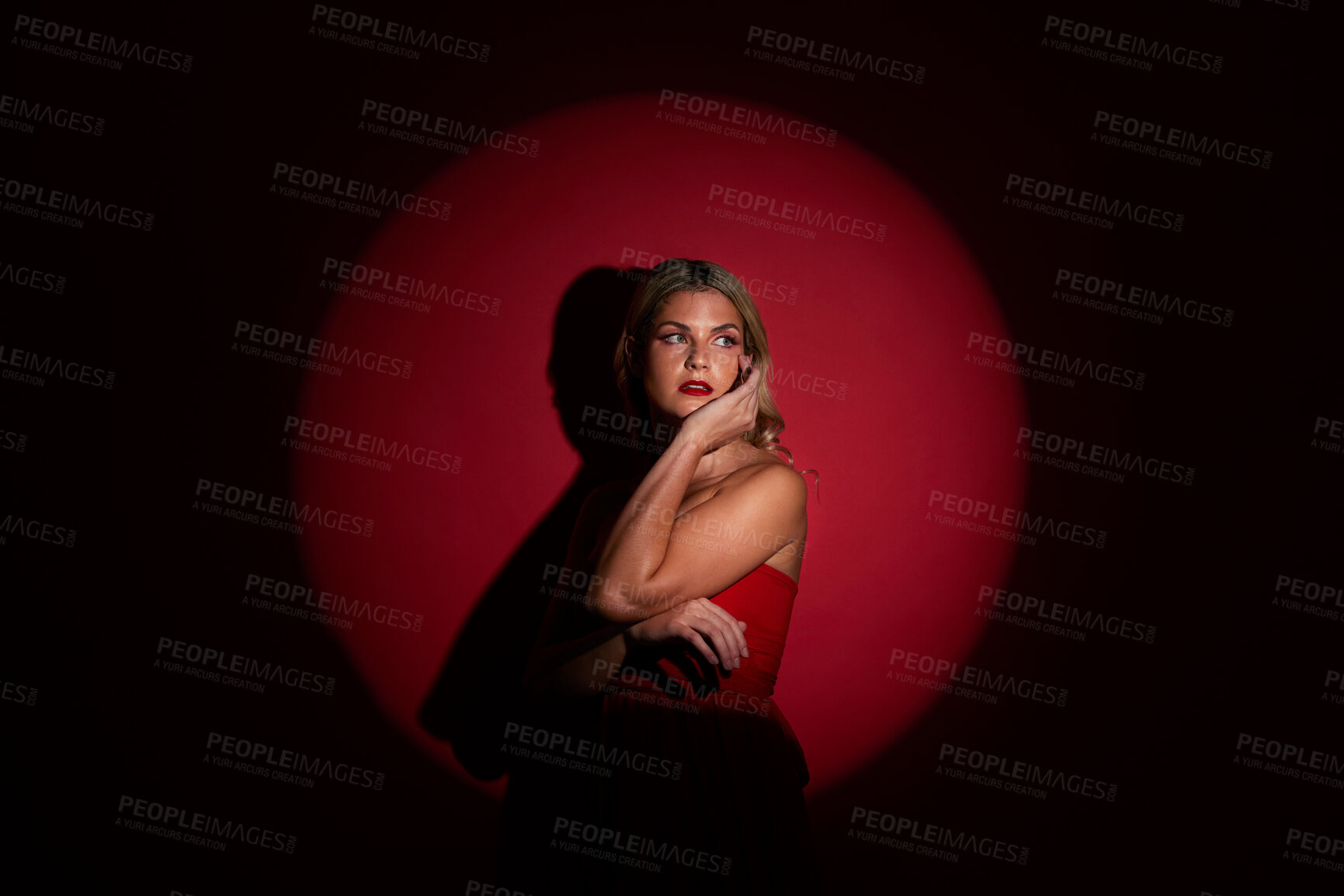 Buy stock photo Fashion, spotlight and red with a model woman in studio on a dark background for classy elegance or style. Beauty, aesthetic and luxury with a confident young female person standing in a dress