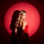 Beauty, spotlight and red with a model woman in studio on a dark background for classy elegance or style. Fashion, aesthetic and luxury with a confident young female person standing in a dress