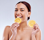 Woman, eating orange and nutrition with beauty, skincare and natural cosmetics on white background. Happy, female model and citrus fruit, vitamin c and healthy food, skin glow and portrait in studio