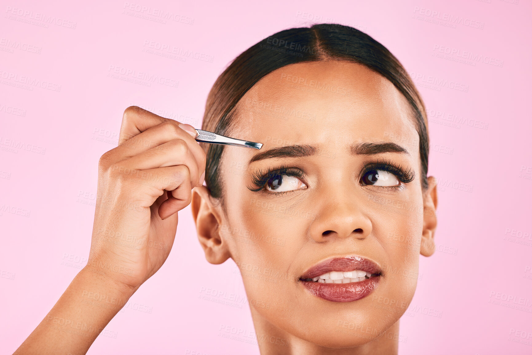 Buy stock photo Pain, face and woman with tweezer for hair removal in studio isolated on a pink background. Beauty, facial and eyebrow plucking of model for self care, skincare and wellness, aesthetic and cosmetic