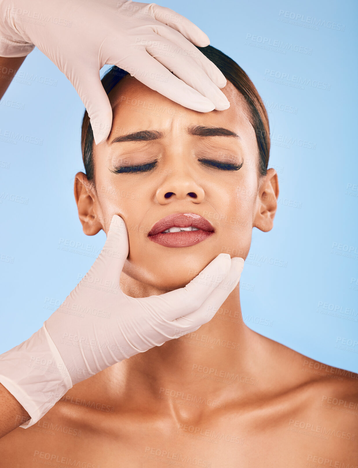 Buy stock photo Plastic surgery, hands and woman in pain for skincare in studio isolated on a blue background. Beauty, dermatology or model with doctor for cosmetic transformation, aesthetic change or face treatment