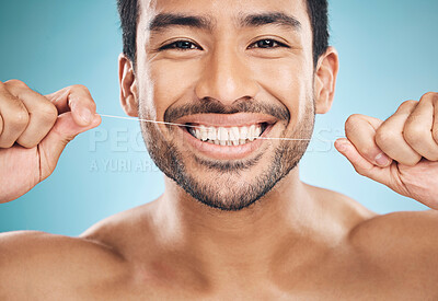 Wellness, teeth and flossing of a man portrait with cleaning and dental health in a studio. Face, blue background and healthy male person with dental floss for mouth hygiene and healthcare with smile