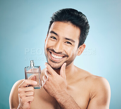 Buy stock photo Portrait, perfume and man with cologne, self care and grooming against a blue studio background. Face, male person and model with wellness, luxury and aesthetic with skincare and fragrance bottle