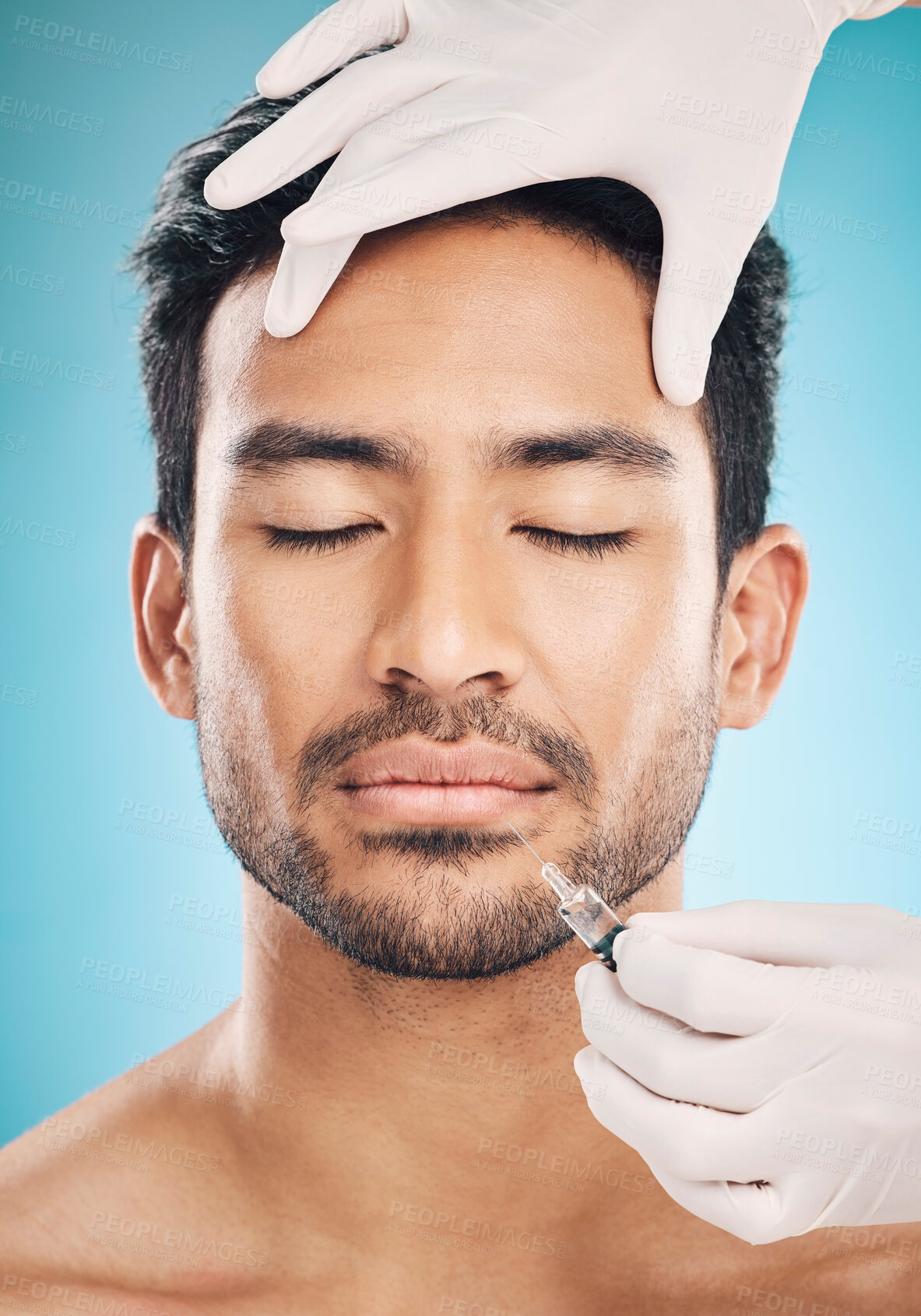 Buy stock photo Face, hands and botox with a plastic surgery man in studio on a blue background for beauty enhancement. Aesthetic, transformation or change with a young patient eyes closed in a clinic for skincare